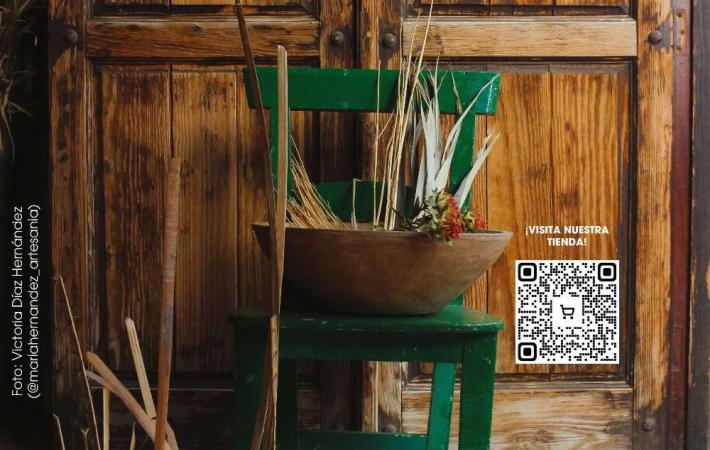 Al fondo una puerta de madera y al frente de la imagen una silla verde con distintos materiales de artesanía tradicional canaria.